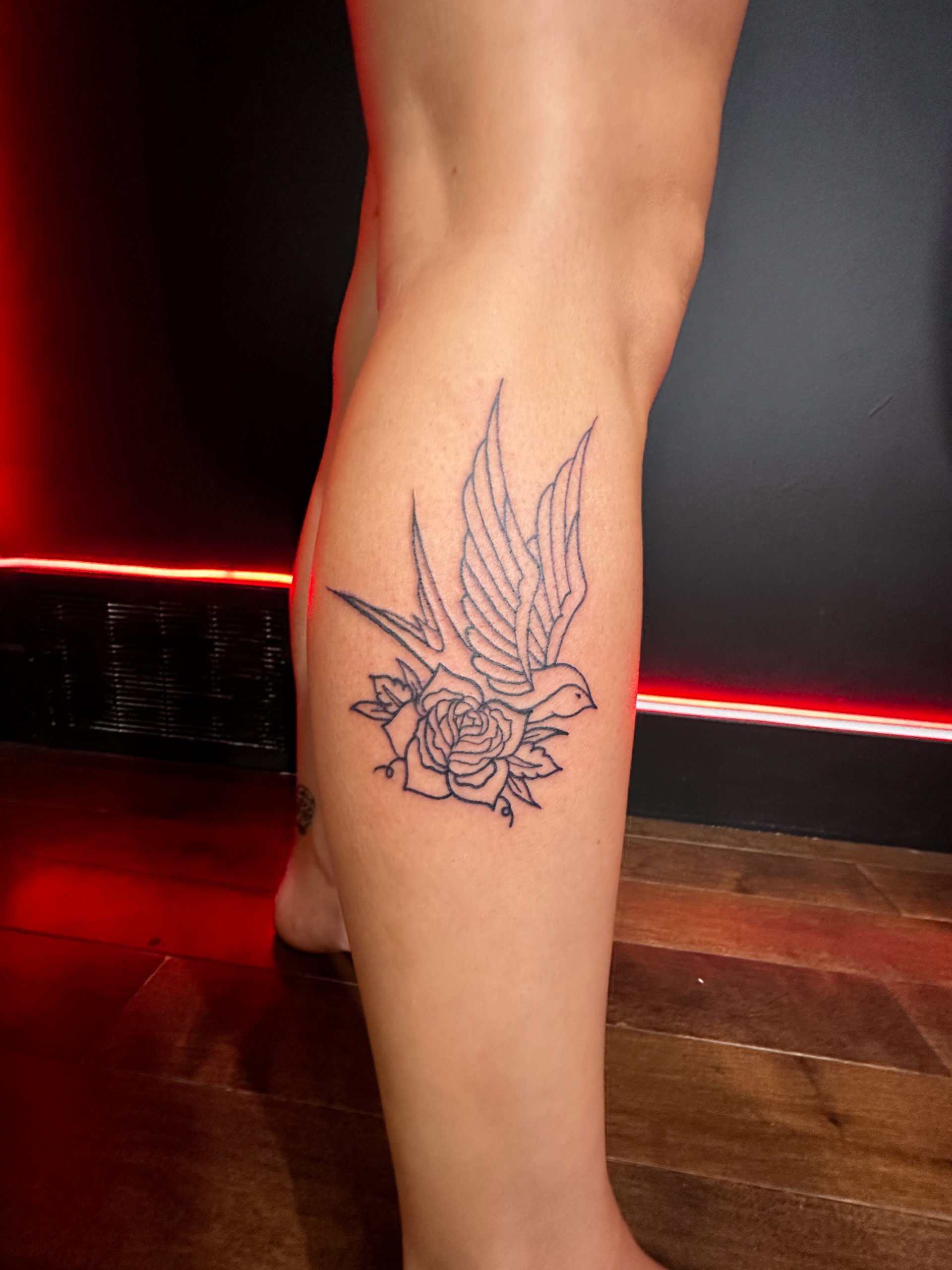 Picture of a traditional swallow and rose leg tattoo.